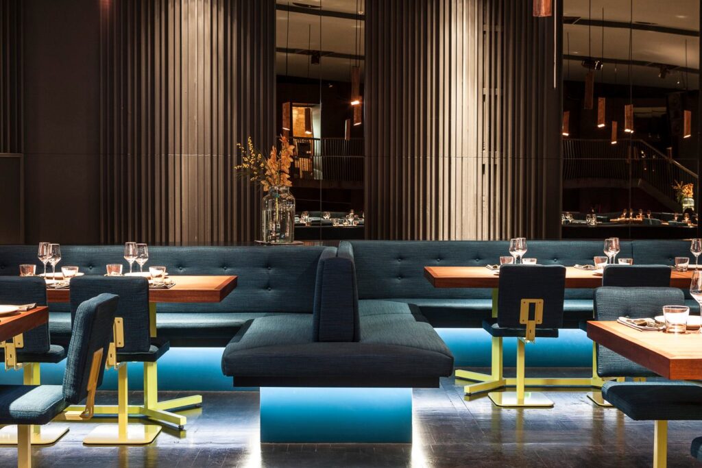 Modernes Restaurant mit stilvollem Interieur, dunkelblauen Polsterbänken und gedämpfter Beleuchtung, eine exklusive Wahl für zum Geburtstag feiern in Berlin.