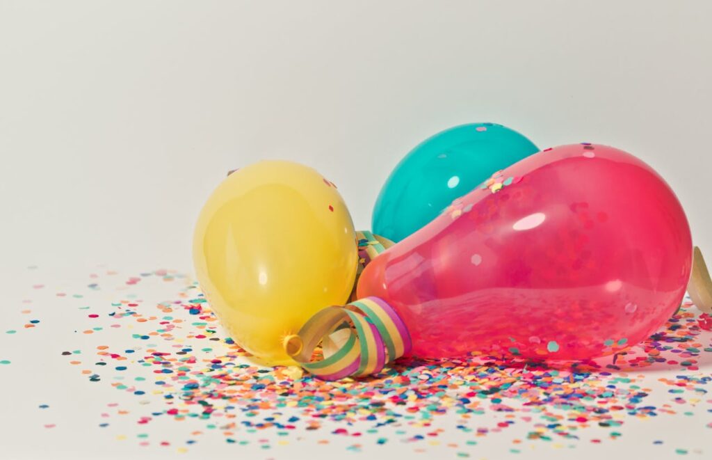 Bunte Luftballons und Konfetti auf einer weißen Oberfläche, die eine festliche Stimmung erzeugen.