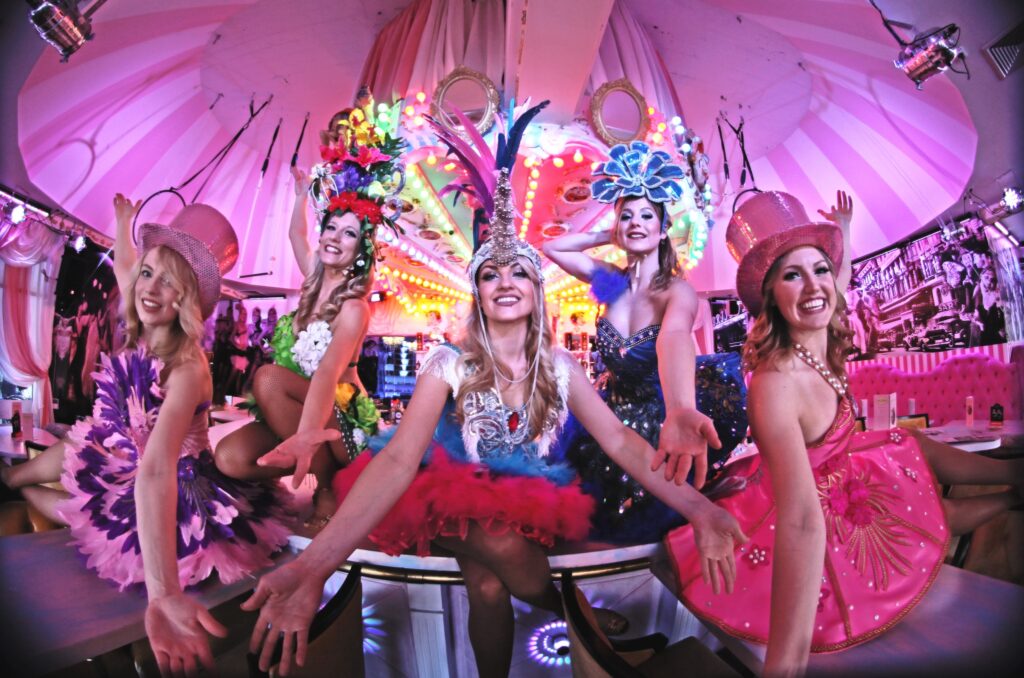 Tänzerinnen in bunten, extravaganten Kostümen und Kopfschmuck in der Wilde Matilde Bar, eine unvergessliche Show für außergewöhnliche Orte zum Geburtstag feiern in Berlin.