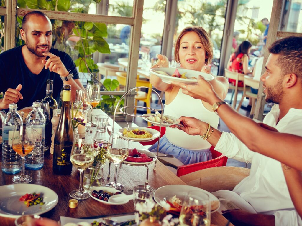 Freunde teilen Speisen im NENI, einem der bekanntesten verrückten Restaurants Berlin mit internationaler Küche.